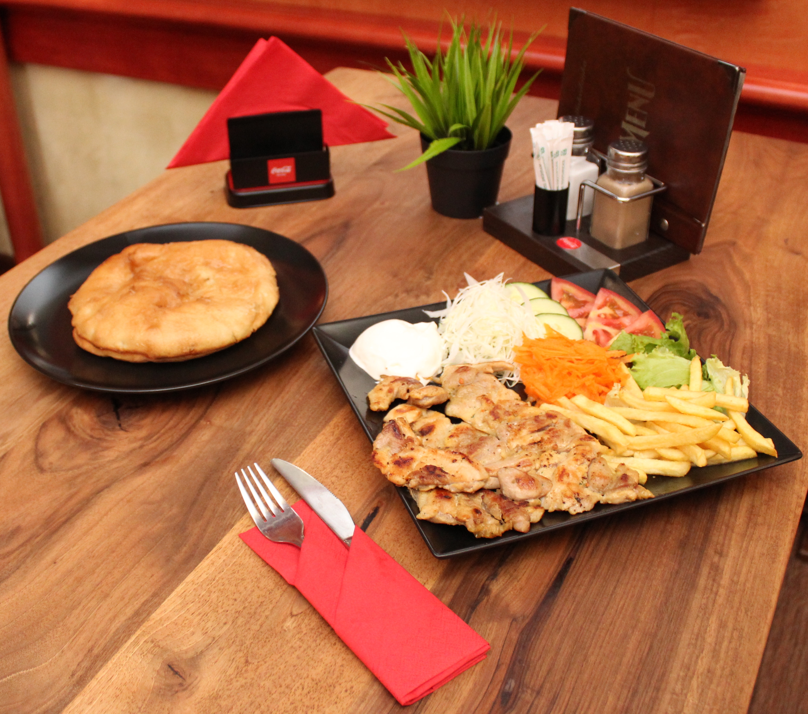 Grilled chicken leg with fries, salad, and flatbread